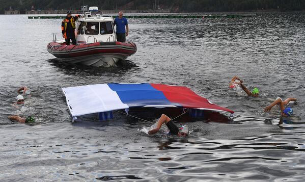 Участники на финише 112-километрового эстафетного заплыва в холодной воде на реке Енисей в честь Дня Государственного флага Российской Федерации в Красноярском крае