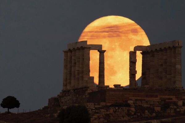 Полная луна восходит за древнегреческим храмом Посейдона на мысе Сунион