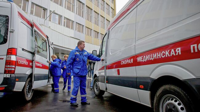 Сотрудники станции скорой и неотложной медицинской помощи у служебных автомобилей