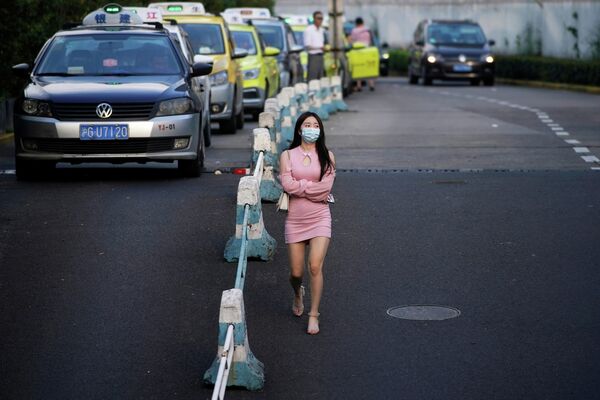 Женщина в защитной маске идет по улице в Шанхае, Китай