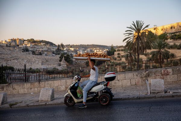Палестинец везёт свежий хлеб на скутере в восточном Иерусалиме