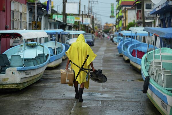 Мужчина идет мимо туристических лодок, которые были вытащены из воды при приближении урагана Грейс в Мексике