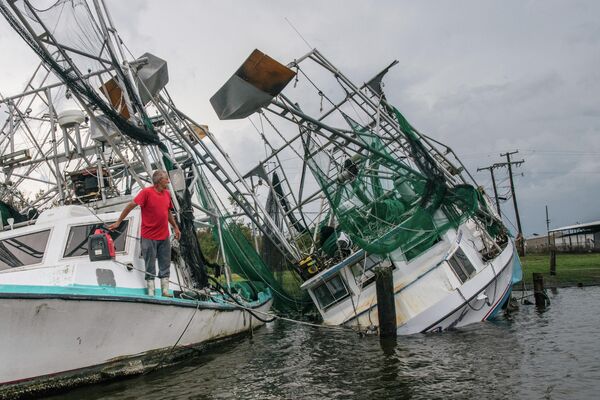 Житель шатата Луизиана смотрит на свою перевернувшуюся лодку после урагана Ида