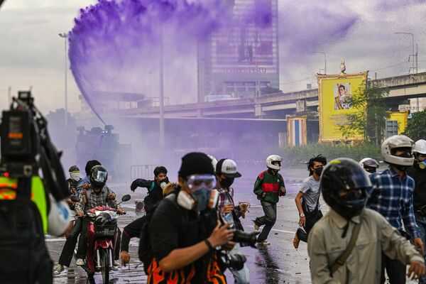 Протестующие бегут после того, как полиция применила водомёт в попытке разогнать их во время демонстрации, призывающей к отставке премьер-министра Таиланда 