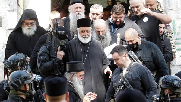 Сотрудники службы безопасности сопровождают Патриарха Портфирия и епископа Иоаникия у монастыря в Цетине, Черногория