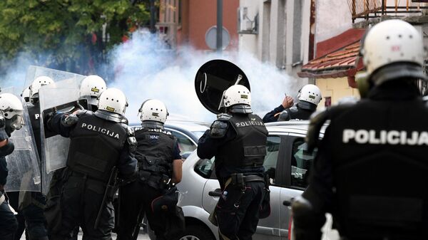Сотрудники полиции стоят в облаке слезоточивого газа во время столкновений на акции протеста против интронизации митрополита Иоанникия