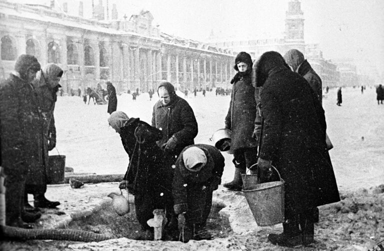 Жители блокадного Ленинграда набирают воду, появившуюся после артобстрела в пробоинах в асфальте на Невском проспекте