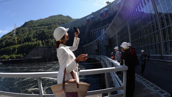 Туристы у здание машинного зала Саяно-Шушенской ГЭС на реке Енисей