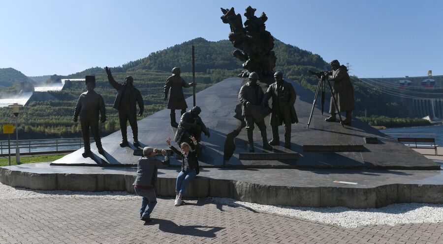 Туристы фотографируются у скульптурной композиции мемориала славы Покорителям Енисея на левобережной смотровой площадке Саяно-Шушенской ГЭС