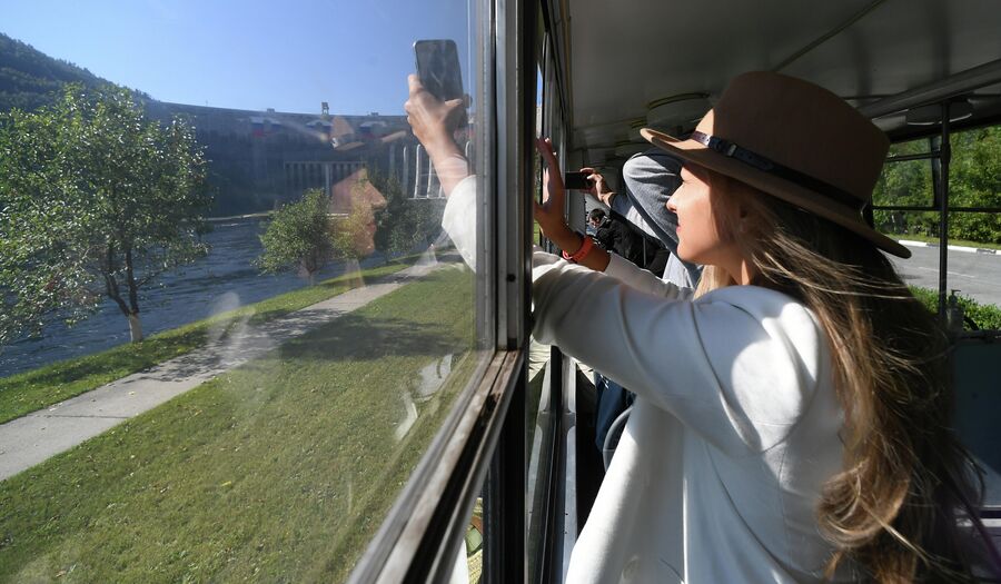 Девушка фотографирует из трамвая плотину Саяно-Шушенской ГЭС на реке Енисей