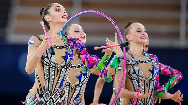 Спортсменки сборной Израиля выполняют упражнения с тремя обручами и двумя парами булав в финале соревнований групп по художественной гимнастике на XXXII летних Олимпийских играх в Токио.