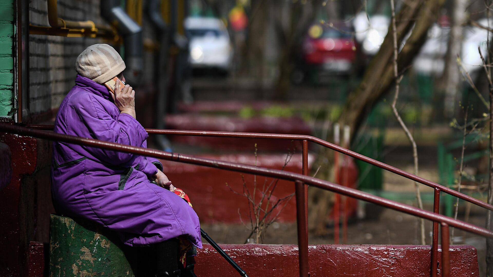 Пожилая женщина разговаривает по мобильному телефону у подъезда своего дома - РИА Новости, 1920, 29.09.2021