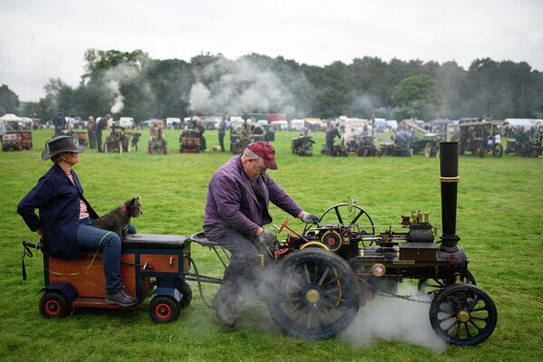 Мужчина управляет транспортным средством с миниатюрным паровым двигателем на фестивале в Малтоне, Великобритания 