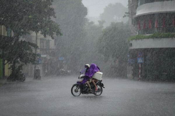 Мотоциклист во время проливного дождя в Ханое, Вьетнам 