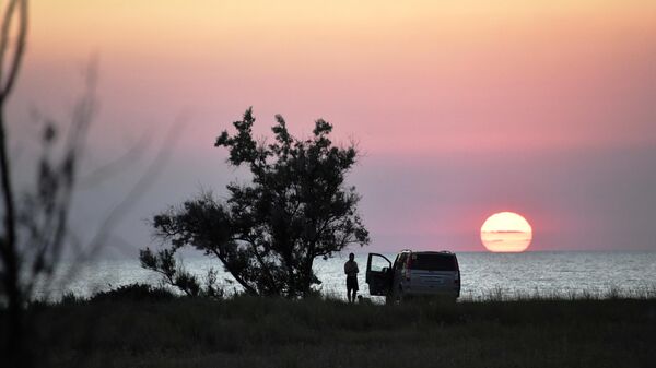 Туристы во время заката на берегу Азовского моря в Республике Крым