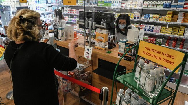 Женщина покупает лекарства в аптеке в Пероле, южная Франция