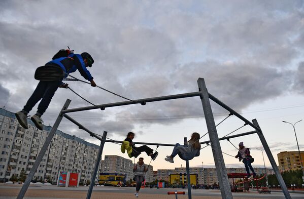 Дети качаются на качелях на площади у бульвара Стрижова в Надыме