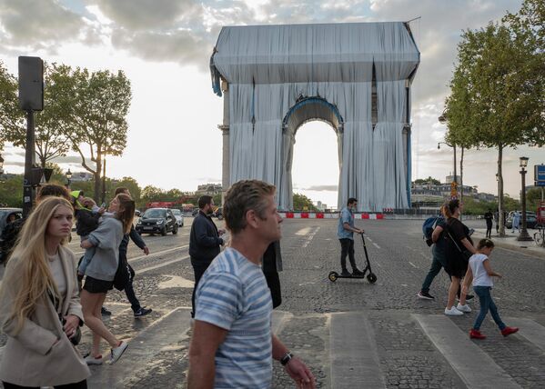 Люди идут мимо закрытой тканью Триумфальной арки в Париже 