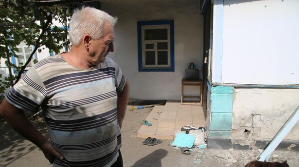 Мужчина во дворе дома, пострадавшего в результате обстрела, в поселке Еленовка Донецкой области