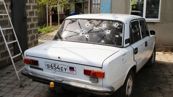 Автомобиль во дворе жилого дома в поселке Еленовка Донецкой области, пострадавший в результате обстрела
