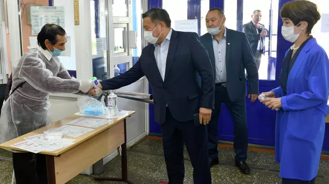 Временно исполняющий обязанности главы Тувы Владислав Ховалыг с супругой Айланой во время измерения температуры перед голосованием на избирательном участке в Кызыле