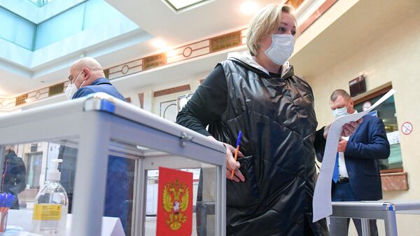 Женщина голосует на выборах депутатов Государственной Думы РФ на избирательном участке в посольстве России в Минске