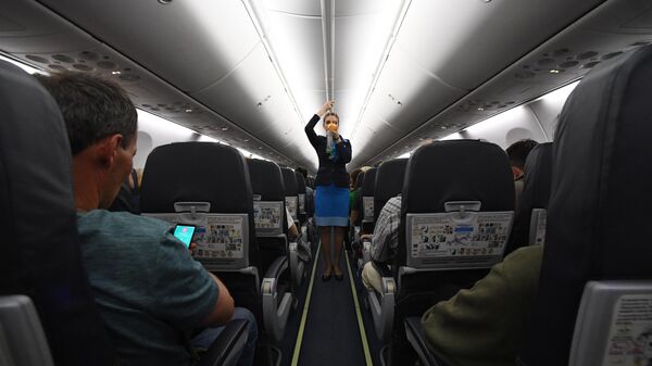 Бортпроводница демонстрирует процедуры для обеспечения безопасности в салоне самолета авиакомпании Победа