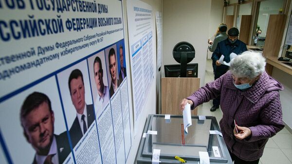 Женщина голосует на выборах депутатов Государственной Думы РФ на избирательном участке №8180 в консульском отделе посольства России в Латвии