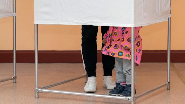 Молодая женщина с дочкой голосуют на избирательном участке №51 на выборах в Госдуму в Петропавловске-Камчатском