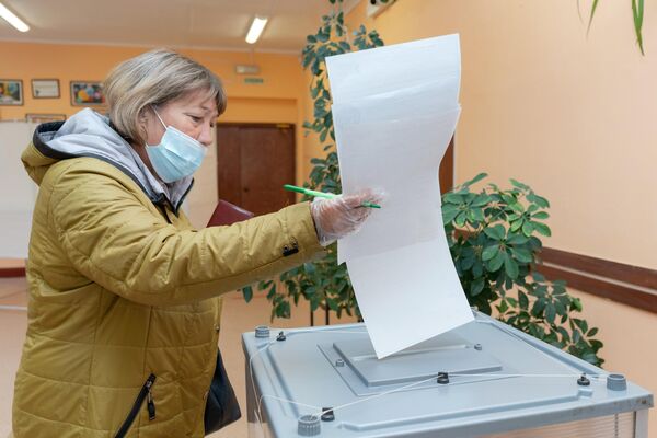 Женщина голосует на выборах депутатов Государственной Думы РФ на избирательном участке №51 в Петропавловске-Камчатском