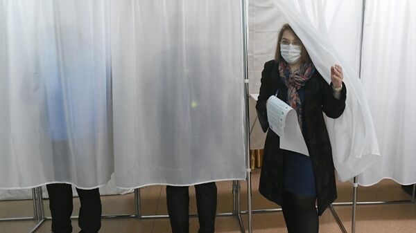 Избирательница выходит из кабины для голосования на избирательном участке 