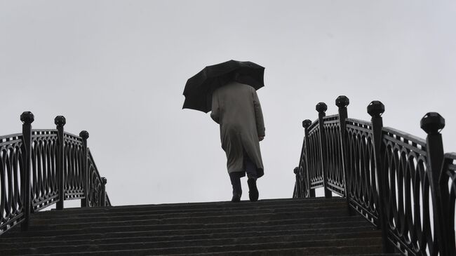 Прохожий на Садовническом мосту во время дождя в Москве