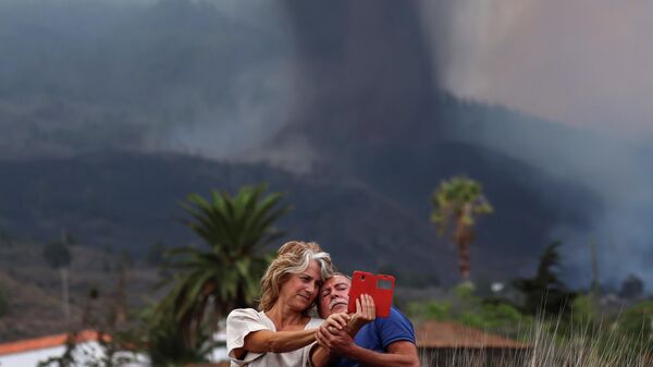 Пара делает селфи перед извергающимся вулканом на канарском острове Ла-Пальма