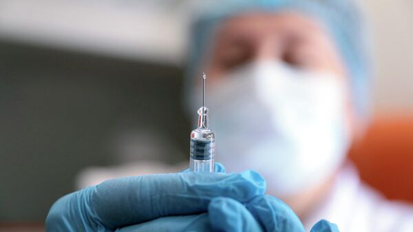 Медик готовит шприц с вакциной против гриппа в пункте вакцинации  360