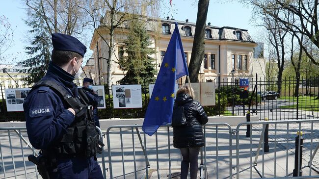 Полицейские и женщина с флагом ЕС у здания Конституционного суда в Варшаве