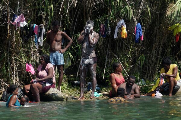 Гаитянские мигранты моются и стирают одежду на берегу Рио-Гранд после того, как они перебрались в Соединенные Штаты из Мексики