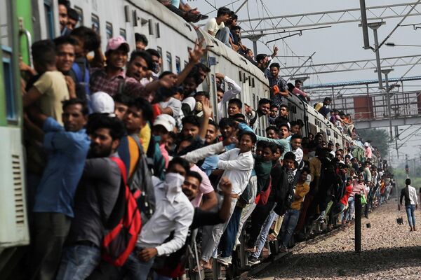 Люди цепляются за переполненный поезд, когда он покидает вокзал во время продолжающейся вспышки коронавирусной болезни (COVID-19) в Газиабаде, Индия
