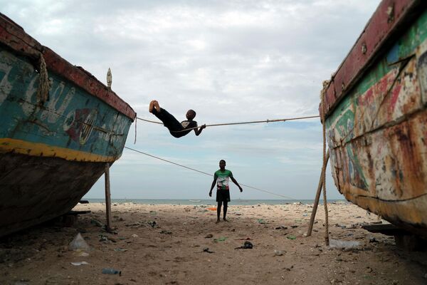 Дети играют на заваленном мусором пляже в Сенегале