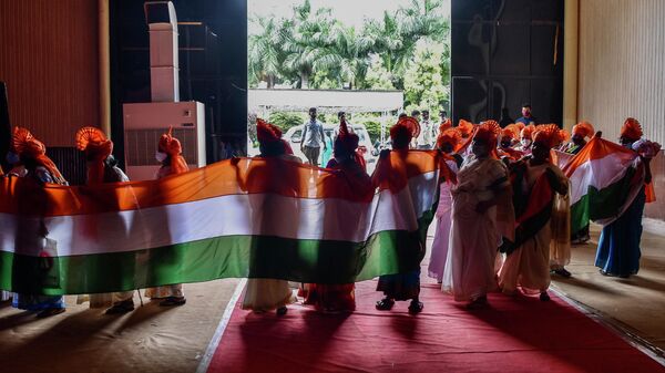 Женщины в традиционной одежде держат флаг по случаю празднования Дня независимости Индии в Бангалоре