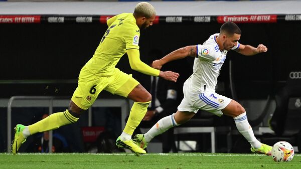 Villarreal's French midfielder Etienne Capoue (L) challenges Real Madrid's Belgian forward Eden Hazard during the Spanish League football match between Real Madrid and Villarreal CF at the Santiago Bernabeu stadium in Madrid on September 25, 2021. (Photo by GABRIEL BOUYS / AFP)