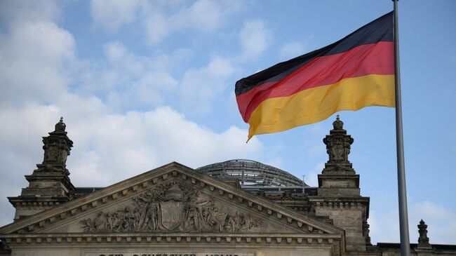 Национальный флаг Федеративной Республики Германия над зданием бундестага в Берлине