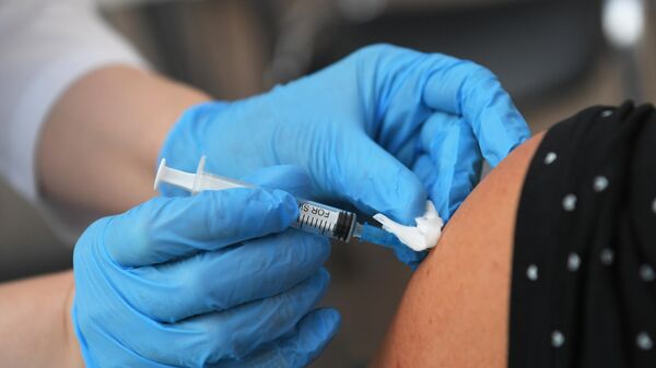 Медицинский работник делает женщине прививку в центре вакцинации от COVID-19