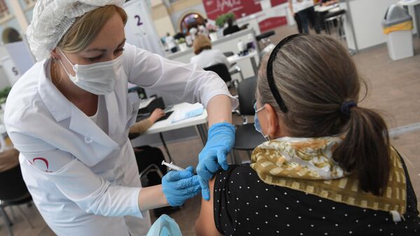 Медицинский работник делает женщине прививку в центре вакцинации от COVID-19 в Гостином дворе в Москве