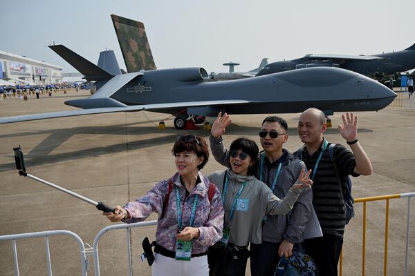 Посетители фотографируются перед высотным разведывательным беспилотником WZ-7 на выставке Airshow China в Чжухае