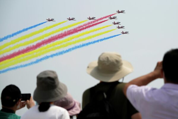 Люди наблюдают за выступлением пилотажной группы китайских ВВС Red Falco на выставке Airshow China в Чжухае