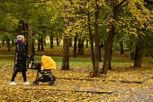 Женщина с коляской во время прогулки в парке Красная Пресня в Москве