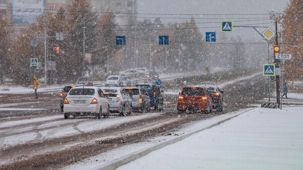 Движение автомобилей на одной из улиц во время снегопада в Нерюнгри