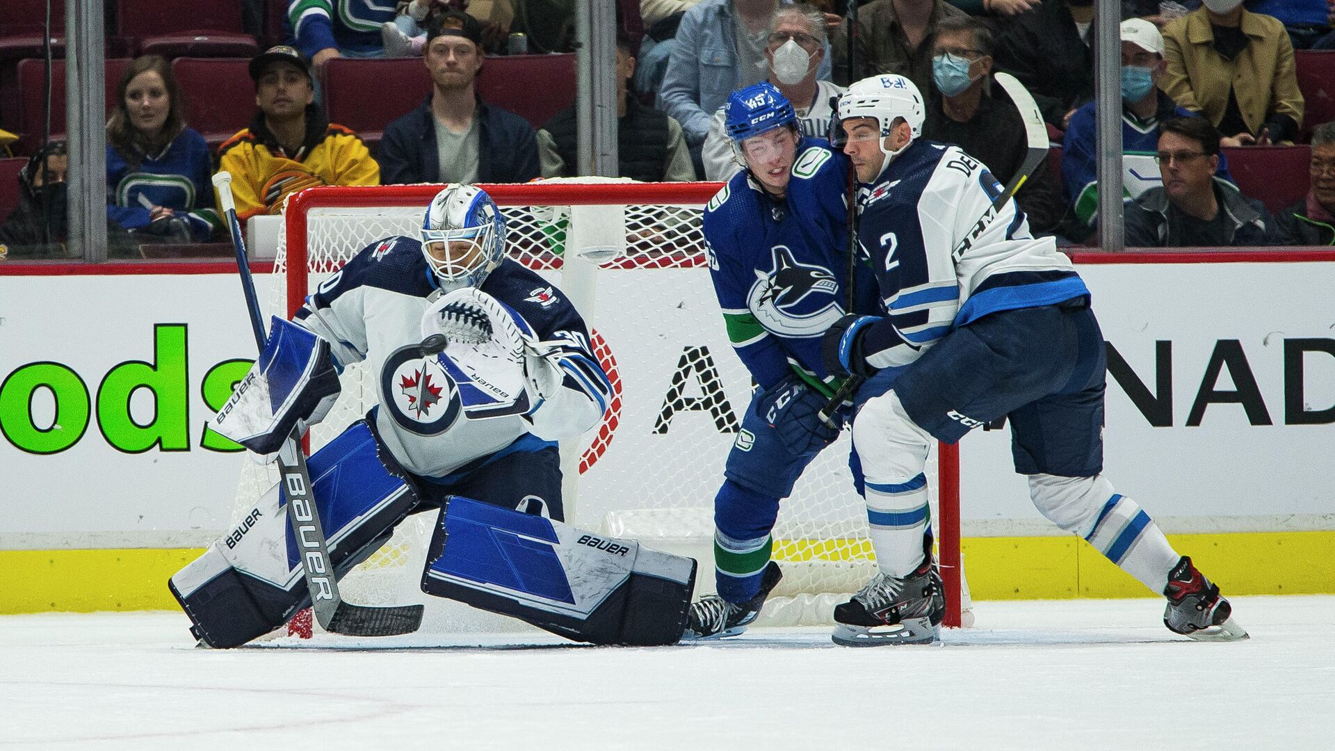 Oct 3, 2021; Vancouver, British Columbia, CAN; Winnipeg Jets goalie Mikhail Berdin (30) makes a save as defenseman Dylan DeMelo (2) checks Vancouver Canucks forward Carson Focht (45) in the first period at Rogers Arena. Mandatory Credit: Bob Frid-USA TODAY Sports - РИА Новости, 1920, 05.10.2021