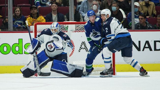 Oct 3, 2021; Vancouver, British Columbia, CAN; Winnipeg Jets goalie Mikhail Berdin (30) makes a save as defenseman Dylan DeMelo (2) checks Vancouver Canucks forward Carson Focht (45) in the first period at Rogers Arena. Mandatory Credit: Bob Frid-USA TODAY Sports