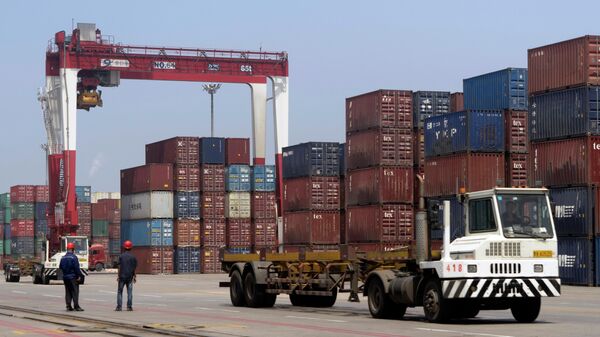 Грузовик проезжает мимо транспортных контейнеров в порту Китая